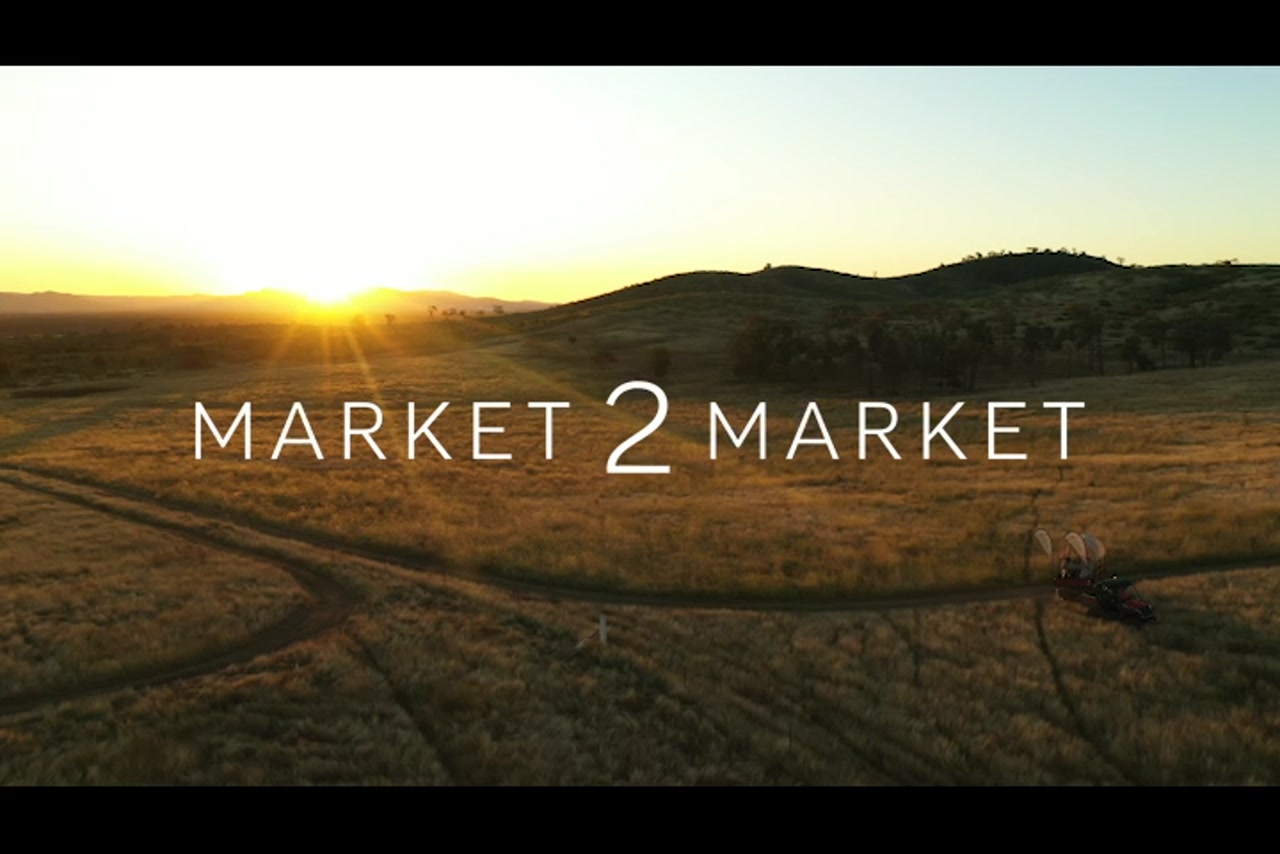 Aerial footage tracking along with small kubota and trailer driving through rural property at dusk.